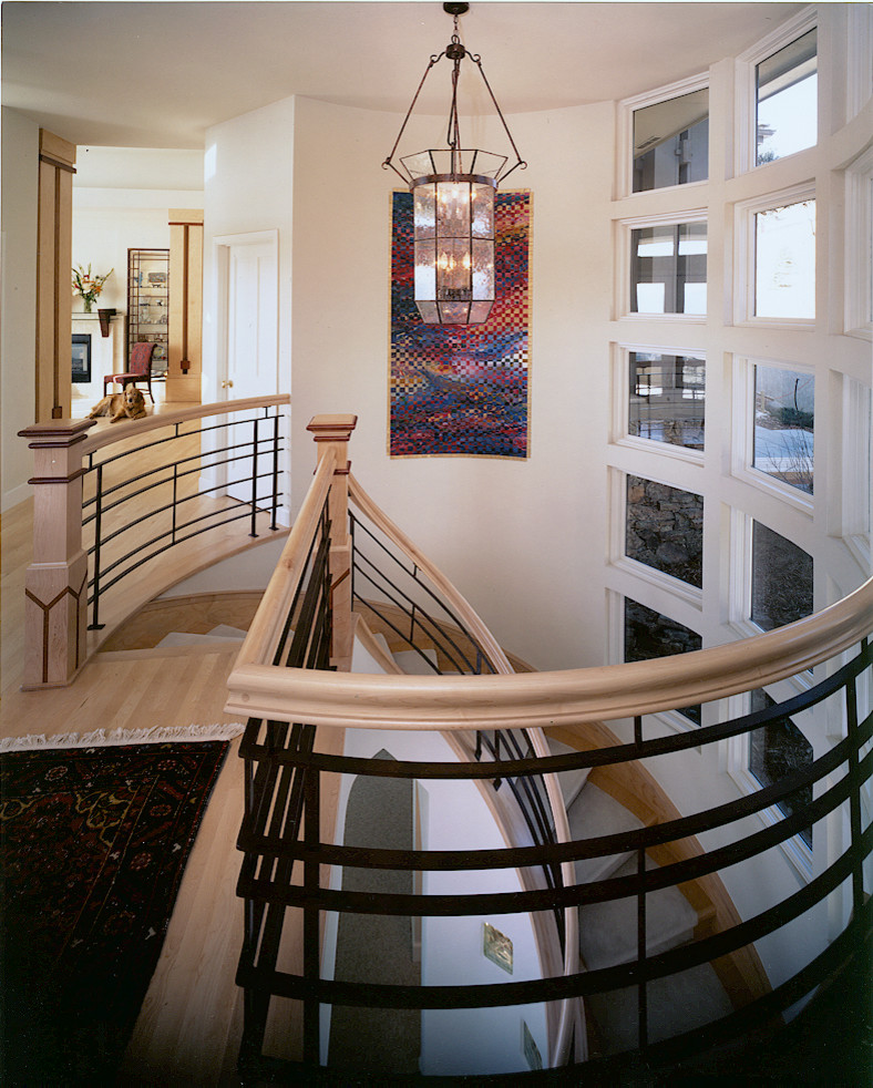 Photo of a large contemporary tile curved staircase in Denver with tile risers and wood railing.