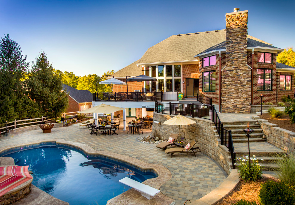 Expansive transitional backyard custom-shaped natural pool in Cincinnati with natural stone pavers and a hot tub.