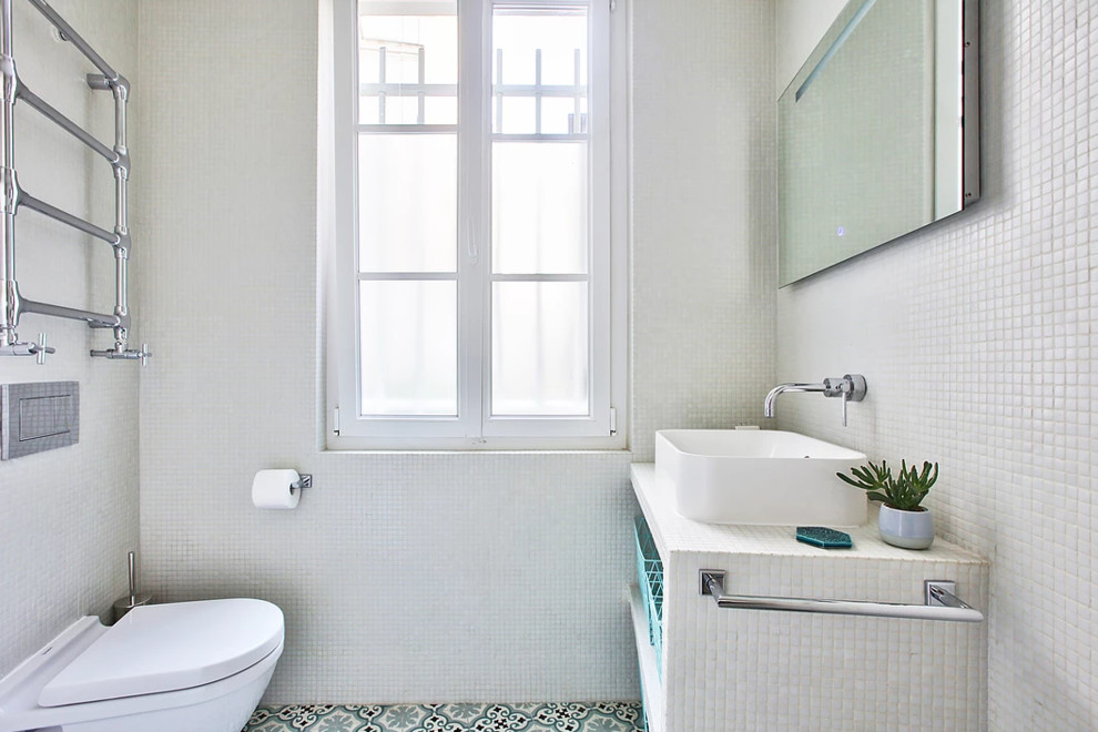 Photo of a small modern 3/4 bathroom in Paris with white cabinets, a curbless shower, a wall-mount toilet, white tile, mosaic tile, white walls, cement tiles, a drop-in sink, blue floor, an open shower, white benchtops and a single vanity.