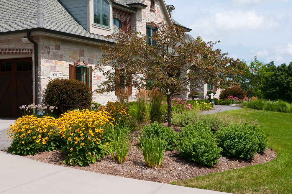 This is an example of a mid-sized traditional front yard full sun driveway for summer in Milwaukee with a garden path and concrete pavers.