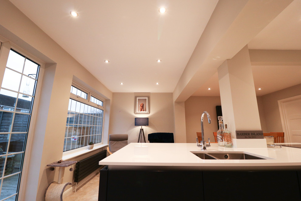 Immagine di una cucina minimal di medie dimensioni con lavello integrato, ante lisce, ante nere, elettrodomestici in acciaio inossidabile, pavimento multicolore e top bianco