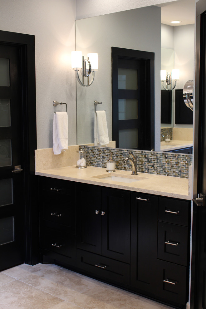 This is an example of a mid-sized transitional master bathroom in Austin with shaker cabinets, dark wood cabinets, limestone benchtops, blue tile, glass tile, a drop-in tub, a corner shower, an undermount sink, blue walls and travertine floors.