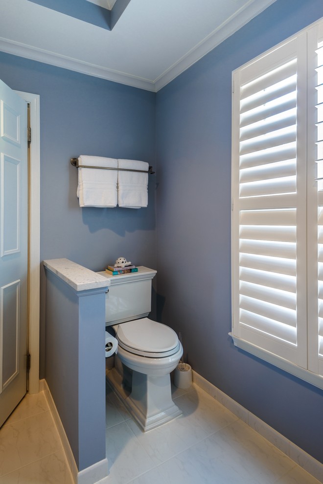 This is an example of a mid-sized contemporary master bathroom in DC Metro with an undermount sink, white cabinets, solid surface benchtops, a corner shower, a two-piece toilet, white tile, ceramic tile, blue walls and ceramic floors.