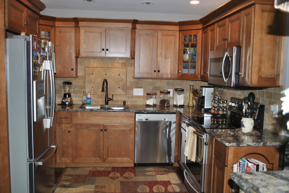 Brown floor kitchen photo with brown cabinets, beige backsplash, stainless steel appliances, an island and gray countertops
