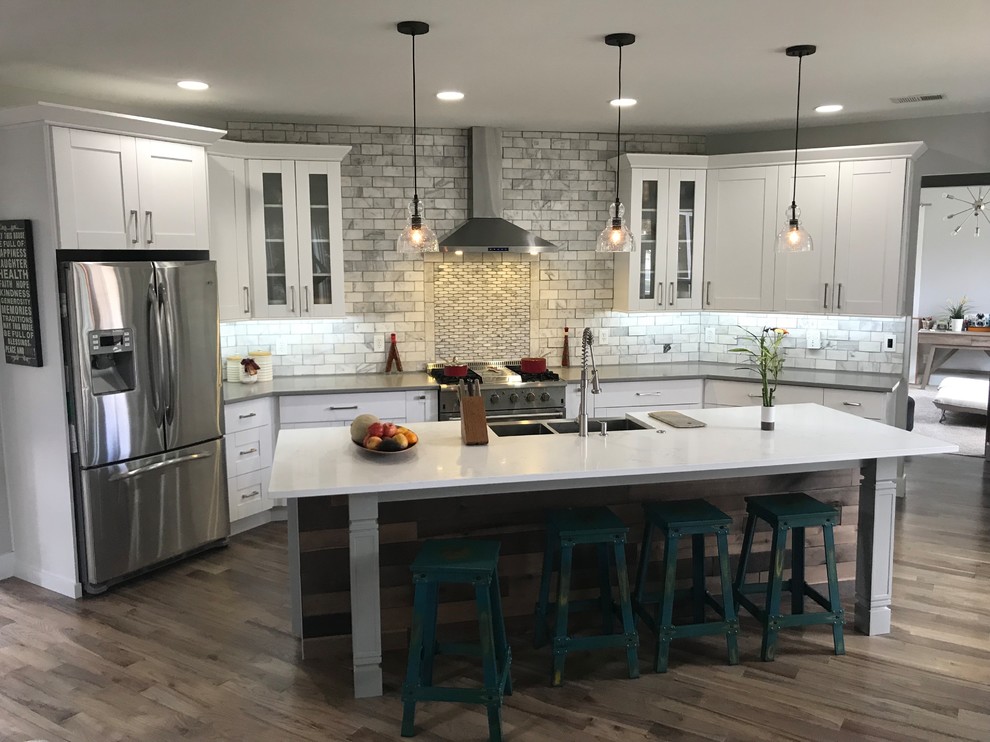 Large transitional single-wall light wood floor and gray floor eat-in kitchen photo in Atlanta with a farmhouse sink, shaker cabinets, white cabinets, quartzite countertops, white backsplash, marble backsplash, stainless steel appliances and white countertops
