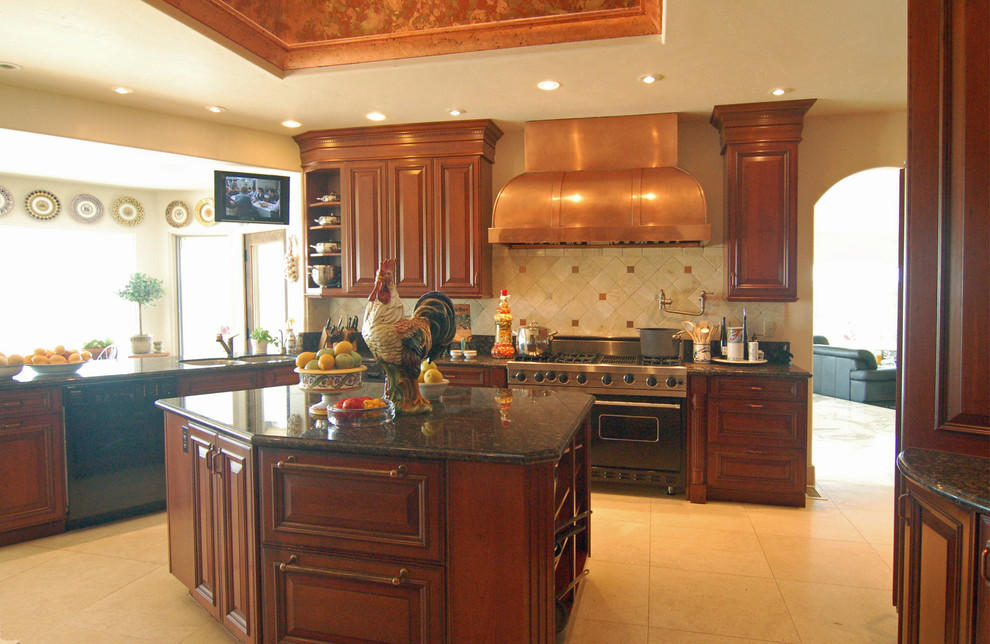 Photo of a large traditional u-shaped separate kitchen in San Luis Obispo with an undermount sink, raised-panel cabinets, red cabinets, granite benchtops, beige splashback, stone tile splashback, panelled appliances, ceramic floors and multiple islands.