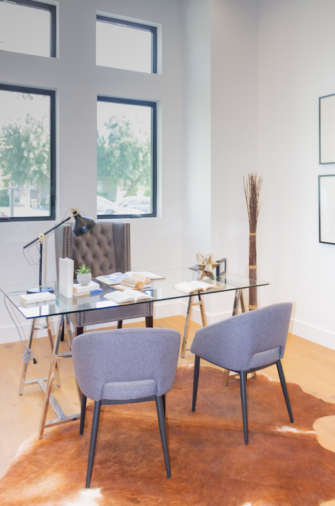 This is an example of a mid-sized contemporary home studio in Los Angeles with white walls, laminate floors and brown floor.