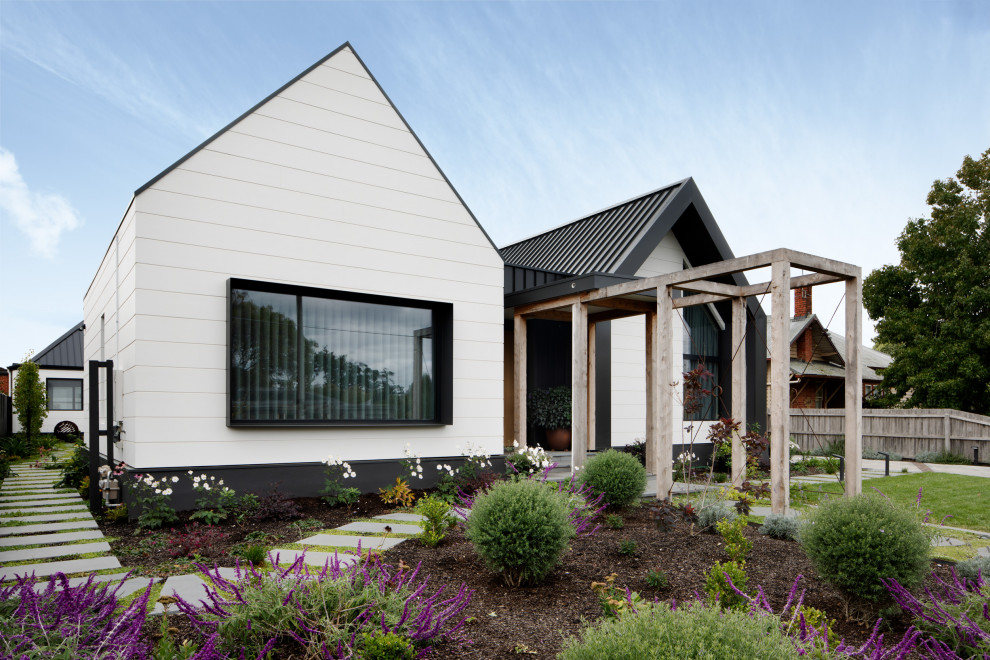 Cette photo montre une très grande façade de maison tendance de plain-pied avec un toit à deux pans, un toit en métal et un toit noir.