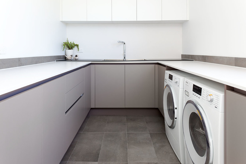 Inspiration for a large contemporary u-shaped laundry room in Perth with solid surface benchtops, white walls and ceramic floors.