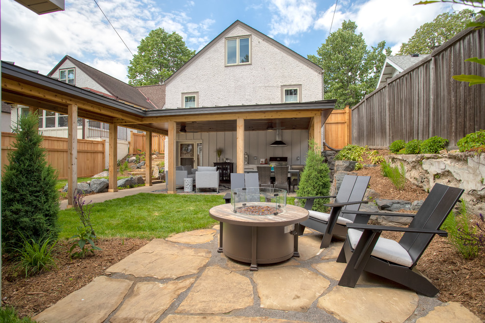 Design ideas for a mid-sized transitional backyard patio in Minneapolis with an outdoor kitchen, stamped concrete and a roof extension.