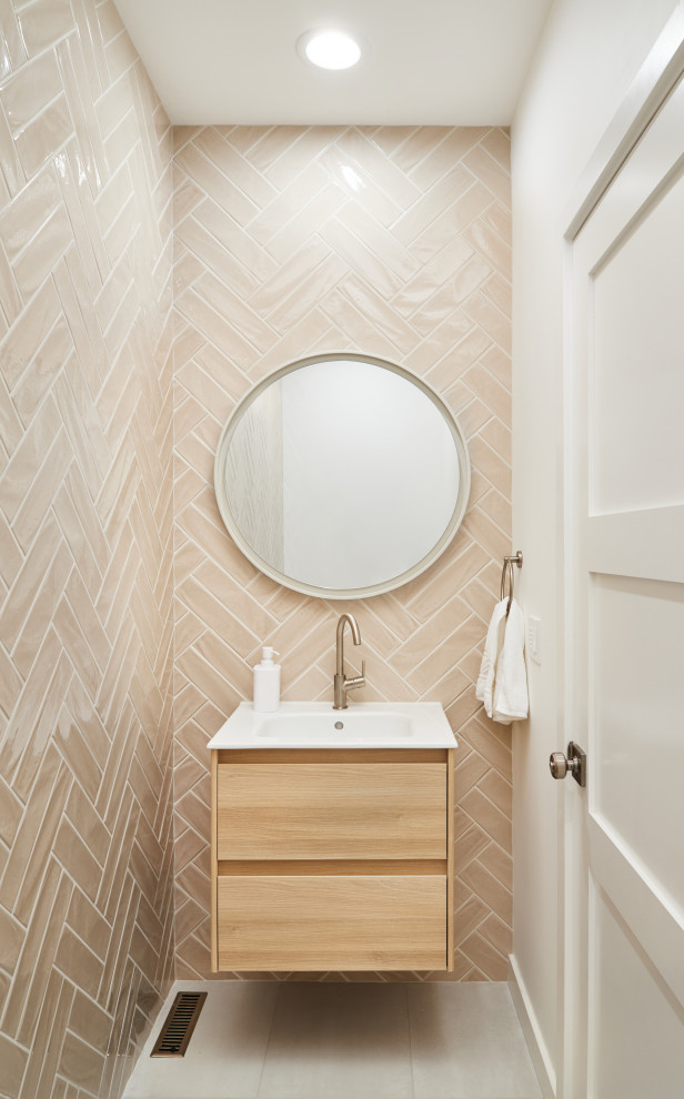 This is an example of a mid-sized transitional powder room in Portland with flat-panel cabinets, light wood cabinets, a two-piece toilet, beige tile, porcelain tile, white walls, concrete floors, an integrated sink, solid surface benchtops, grey floor and white benchtops.