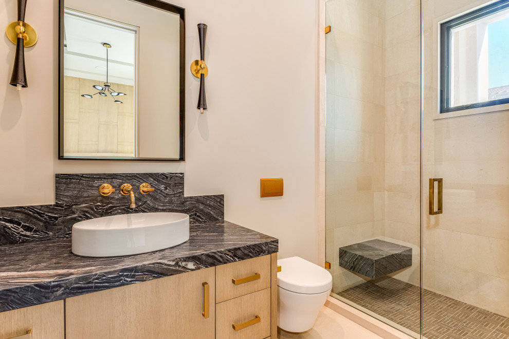 Bathroom - large contemporary 3/4 ceramic tile limestone floor, beige floor and single-sink bathroom idea in Orange County with a hinged shower door, flat-panel cabinets, light wood cabinets, a wall-mount toilet, beige walls, a vessel sink, quartzite countertops, black countertops and a floating vanity