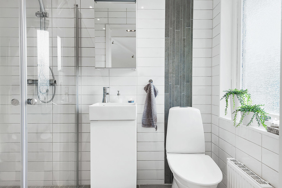 This is an example of a contemporary master bathroom in Malmo with a vessel sink, a two-piece toilet, white tile, flat-panel cabinets, white cabinets, a corner shower, subway tile and white walls.