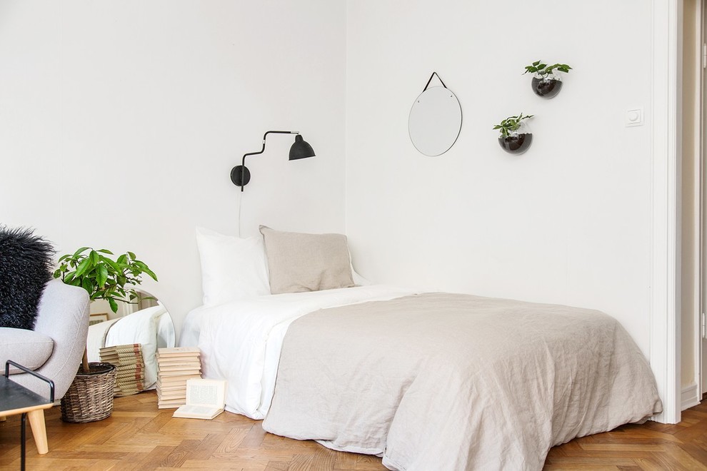 This is an example of a mid-sized scandinavian guest bedroom in Stockholm with white walls and medium hardwood floors.