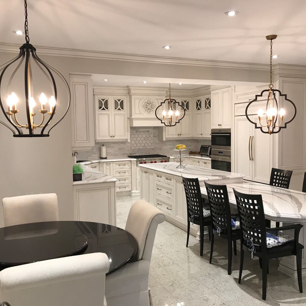 This is an example of an expansive traditional u-shaped eat-in kitchen in Toronto with an undermount sink, recessed-panel cabinets, distressed cabinets, quartz benchtops, white splashback, marble splashback, panelled appliances, with island, white floor and white benchtop.