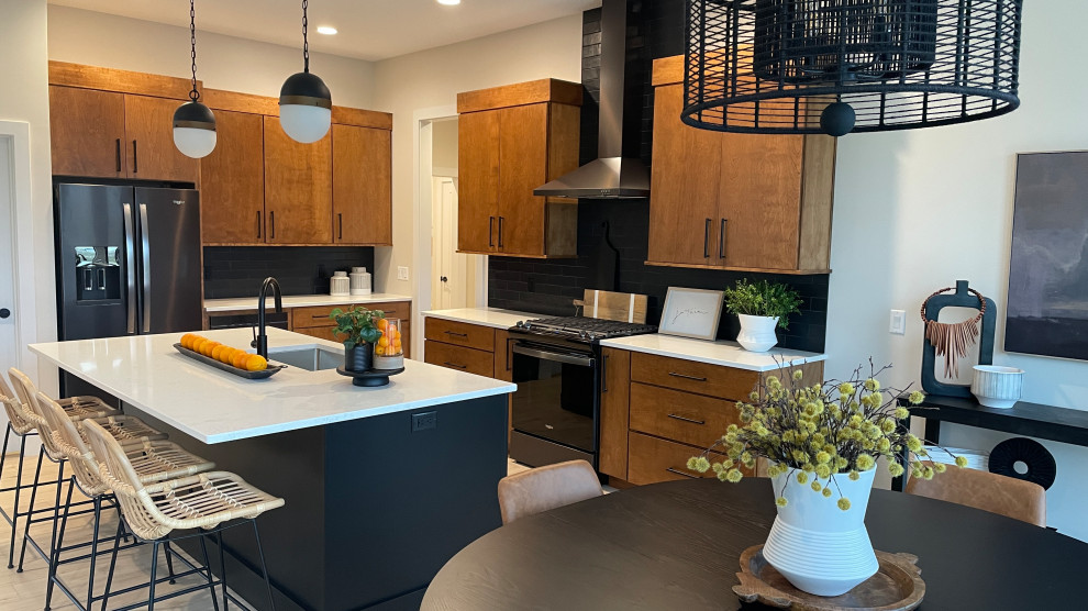 Inspiration for a large midcentury l-shaped open plan kitchen in Other with an undermount sink, flat-panel cabinets, medium wood cabinets, quartz benchtops, black splashback, subway tile splashback, black appliances, light hardwood floors, with island, brown floor and white benchtop.