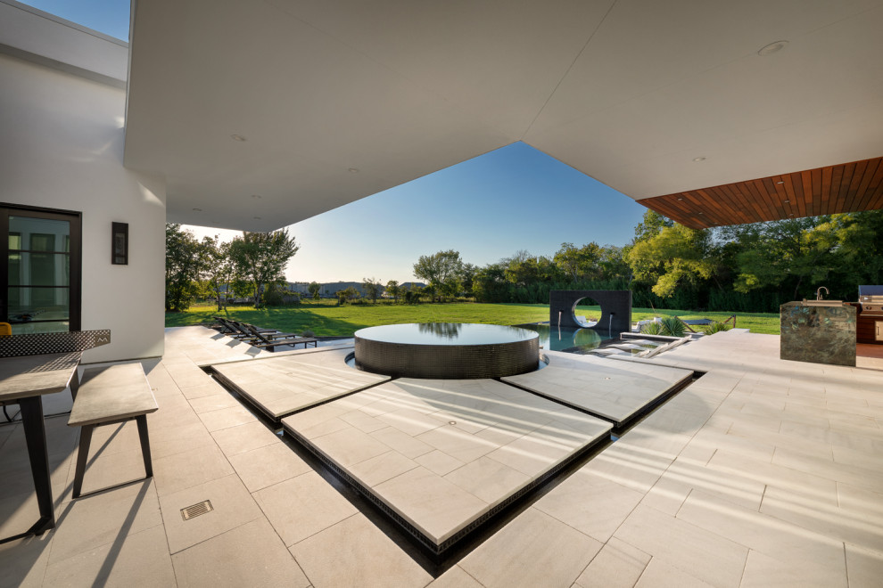 Großer Moderner Infinity-Pool hinter dem Haus in rechteckiger Form mit Natursteinplatten in Houston