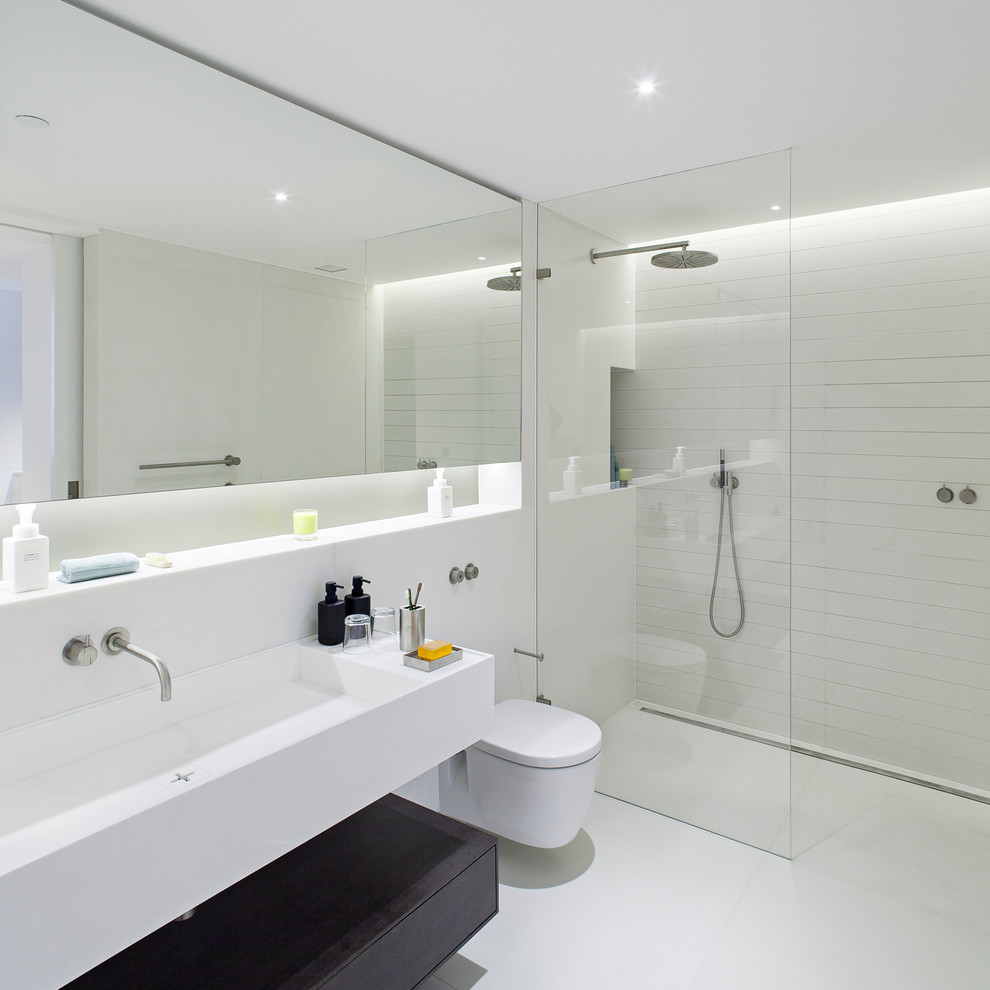 Mid-sized contemporary bathroom in London with a trough sink, a curbless shower, a wall-mount toilet, white tile and white walls.