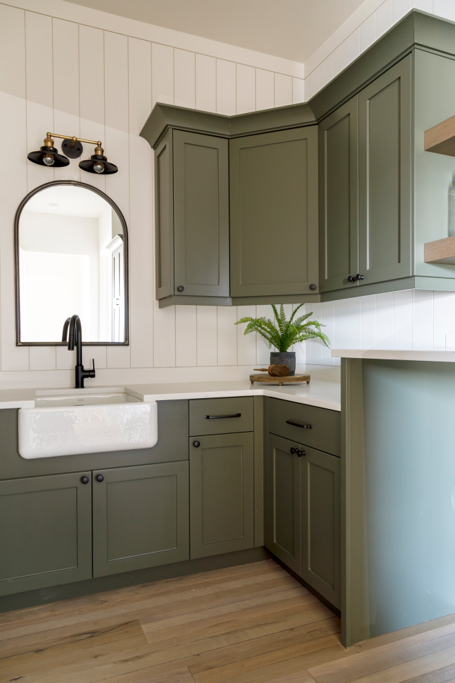Inspiration for a medium sized farmhouse galley utility room in Boise with a belfast sink, shaker cabinets, green cabinets, engineered stone countertops, white splashback, tonge and groove splashback, white walls, medium hardwood flooring, a side by side washer and dryer, white worktops and tongue and groove walls.