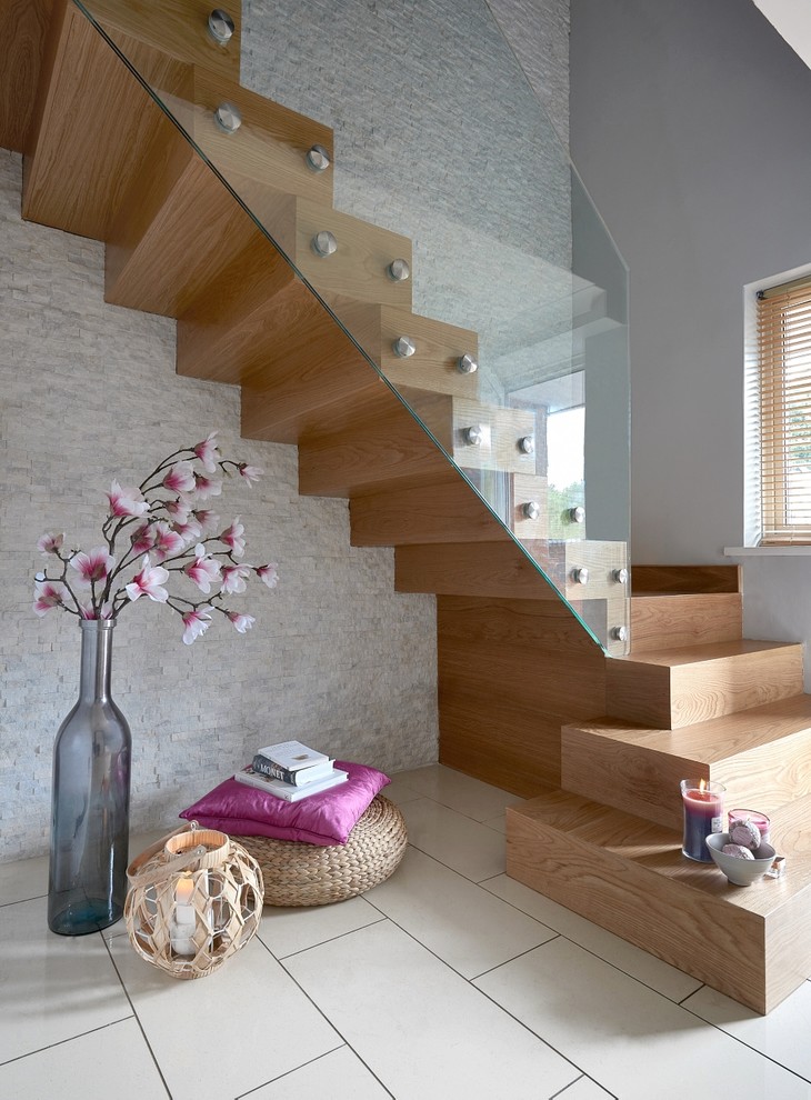 Diseño de escalera suspendida contemporánea grande con escalones de madera, contrahuellas de madera y barandilla de vidrio