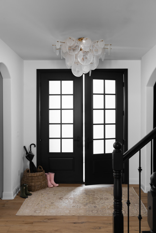 Mid-sized traditional front door in Detroit with white walls, light hardwood floors, a double front door and a black front door.