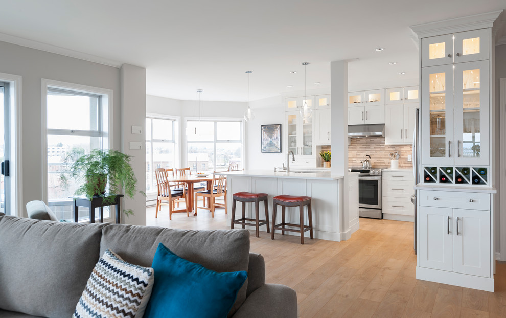 Eat-in kitchen - mid-sized transitional l-shaped laminate floor eat-in kitchen idea in Vancouver with an undermount sink, shaker cabinets, white cabinets, quartz countertops, gray backsplash, glass tile backsplash, stainless steel appliances and an island