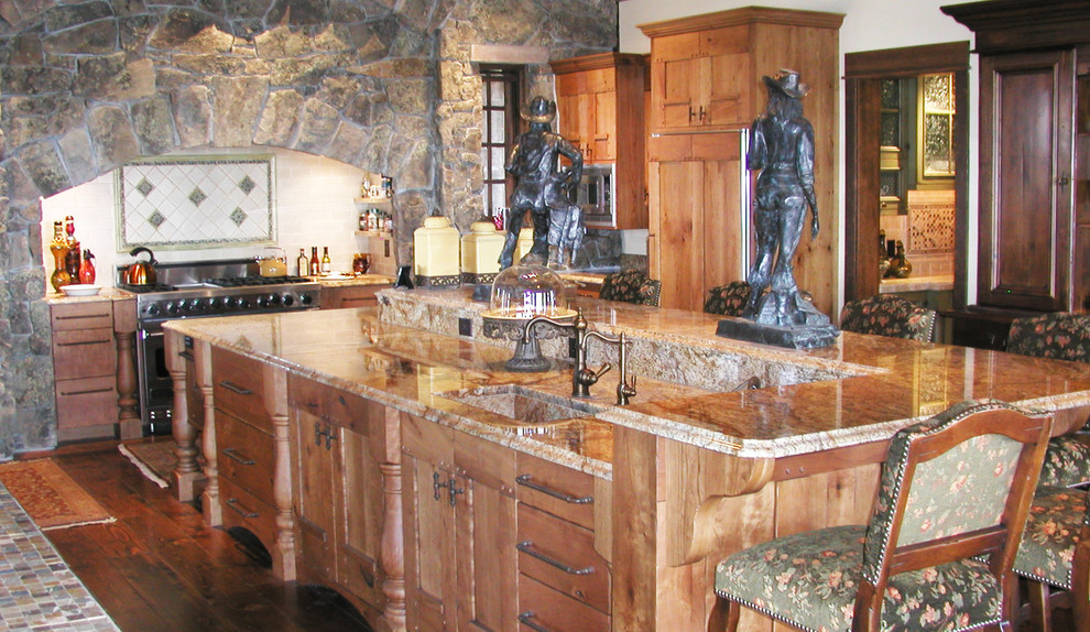 Example of a large mountain style l-shaped medium tone wood floor and brown floor eat-in kitchen design with an undermount sink, shaker cabinets, medium tone wood cabinets, granite countertops, white backsplash, ceramic backsplash, stainless steel appliances and an island