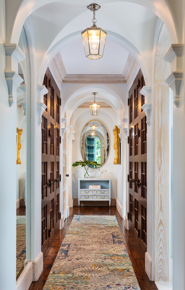 This is an example of a mediterranean hallway in Miami with white walls, dark hardwood floors and brown floor.