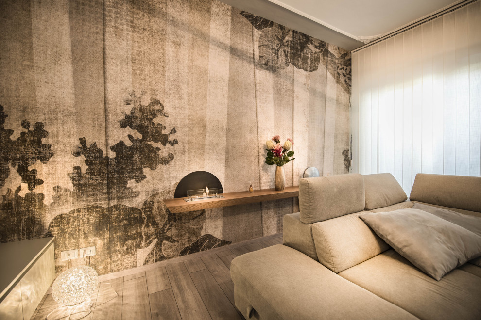 Cette image montre un salon design de taille moyenne et fermé avec un mur blanc, parquet clair, cheminée suspendue, un manteau de cheminée en bois, un sol gris et du papier peint.