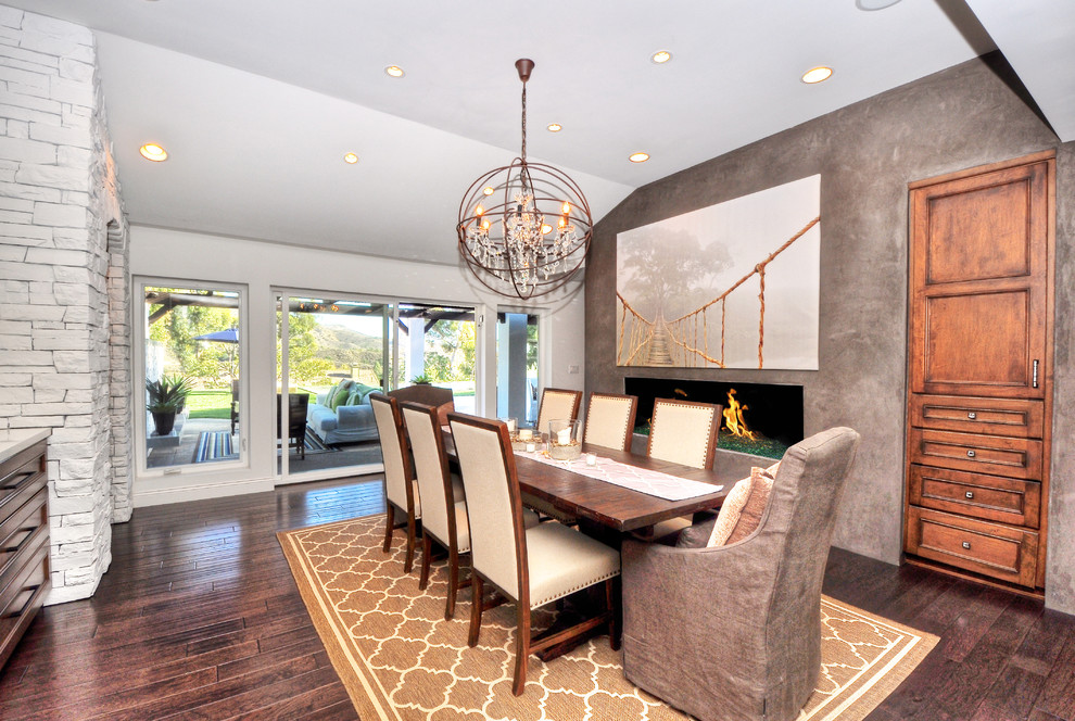 Inspiration for a large transitional separate dining room in Orange County with grey walls, a ribbon fireplace, dark hardwood floors, a concrete fireplace surround and brown floor.