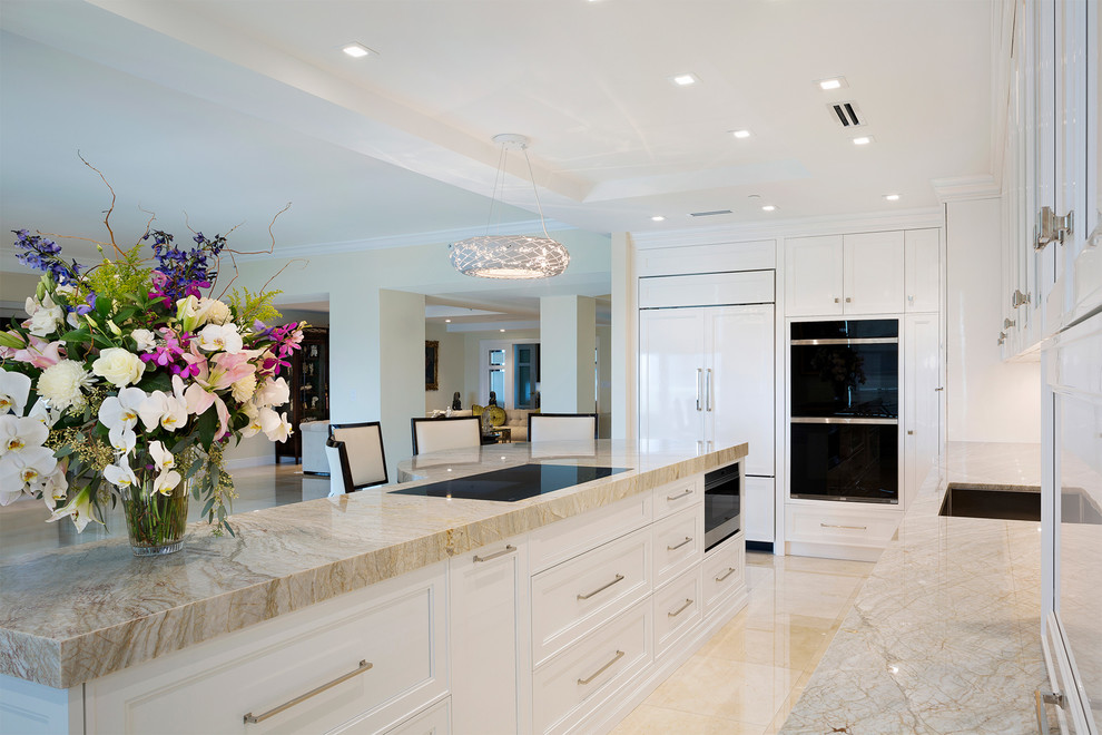 Inspiration for a mid-sized transitional l-shaped porcelain tile and beige floor eat-in kitchen remodel in Miami with an undermount sink, recessed-panel cabinets, white cabinets, marble countertops, beige backsplash, mosaic tile backsplash, stainless steel appliances, an island and beige countertops