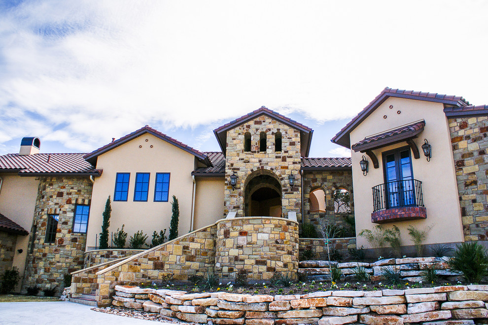 This is an example of a mediterranean two-storey exterior in Austin with stone veneer and a gable roof.