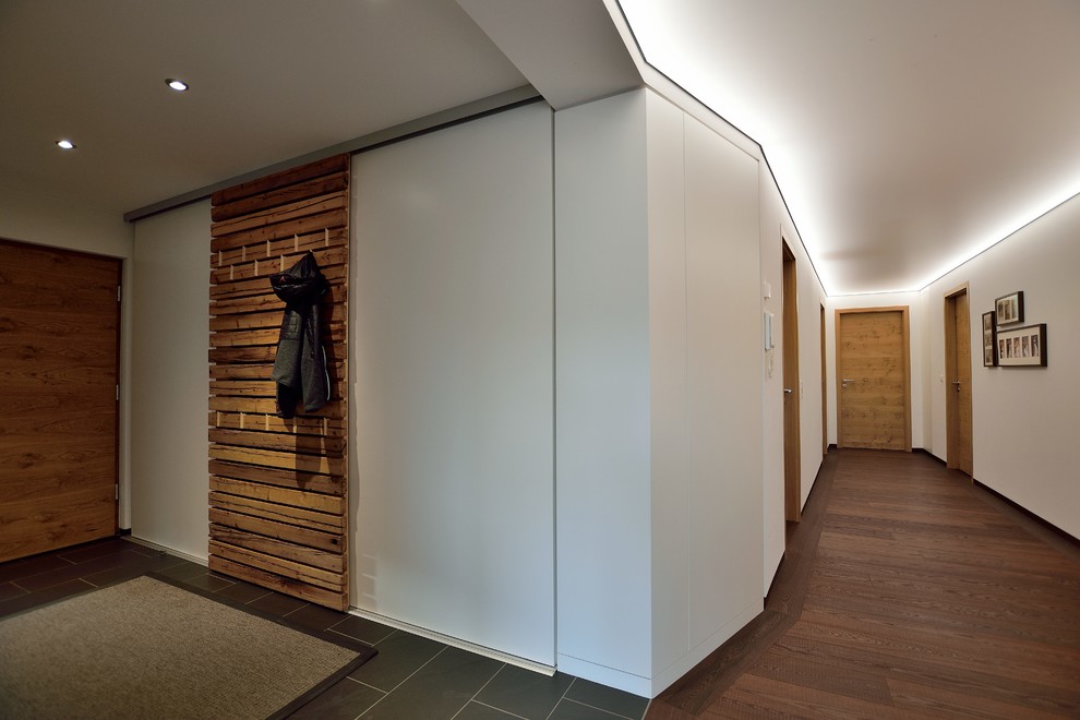 This is an example of a mid-sized contemporary hallway in Other with white walls, dark hardwood floors and brown floor.