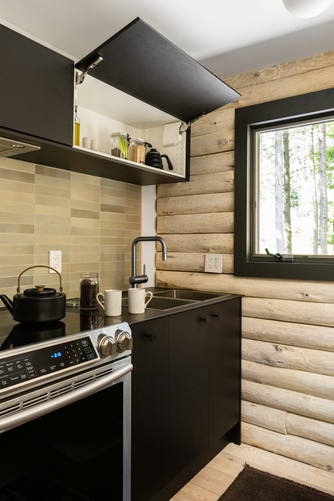 Eat-in kitchen - small 1960s galley plywood floor and exposed beam eat-in kitchen idea in New York with flat-panel cabinets, black cabinets, concrete countertops, beige backsplash and subway tile backsplash
