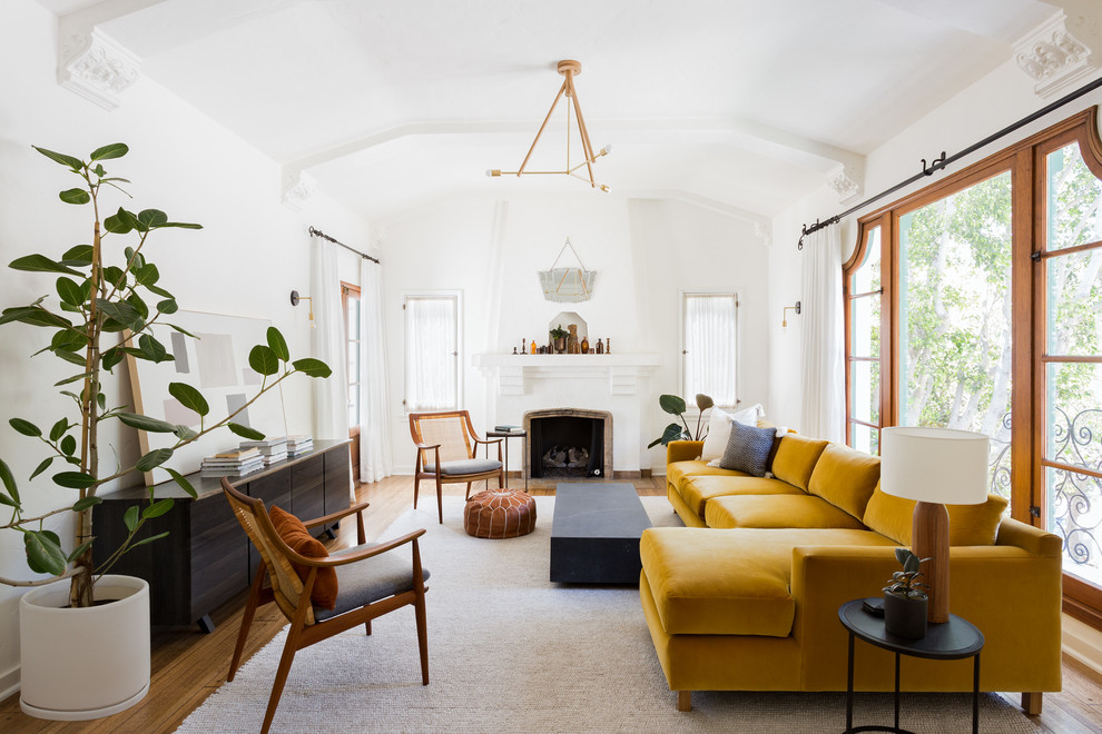 Inspiration for a mid-sized mediterranean open concept living room in Los Angeles with white walls, medium hardwood floors, a standard fireplace, a plaster fireplace surround, no tv and brown floor.