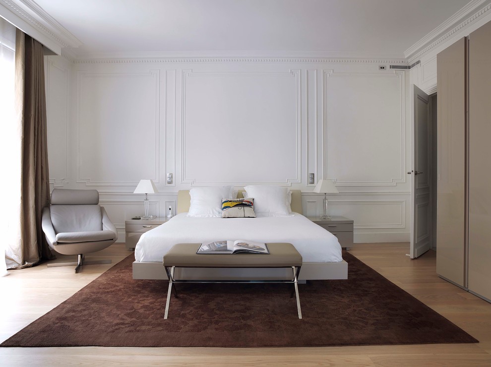 Large contemporary master bedroom in Paris with light hardwood floors and white walls.
