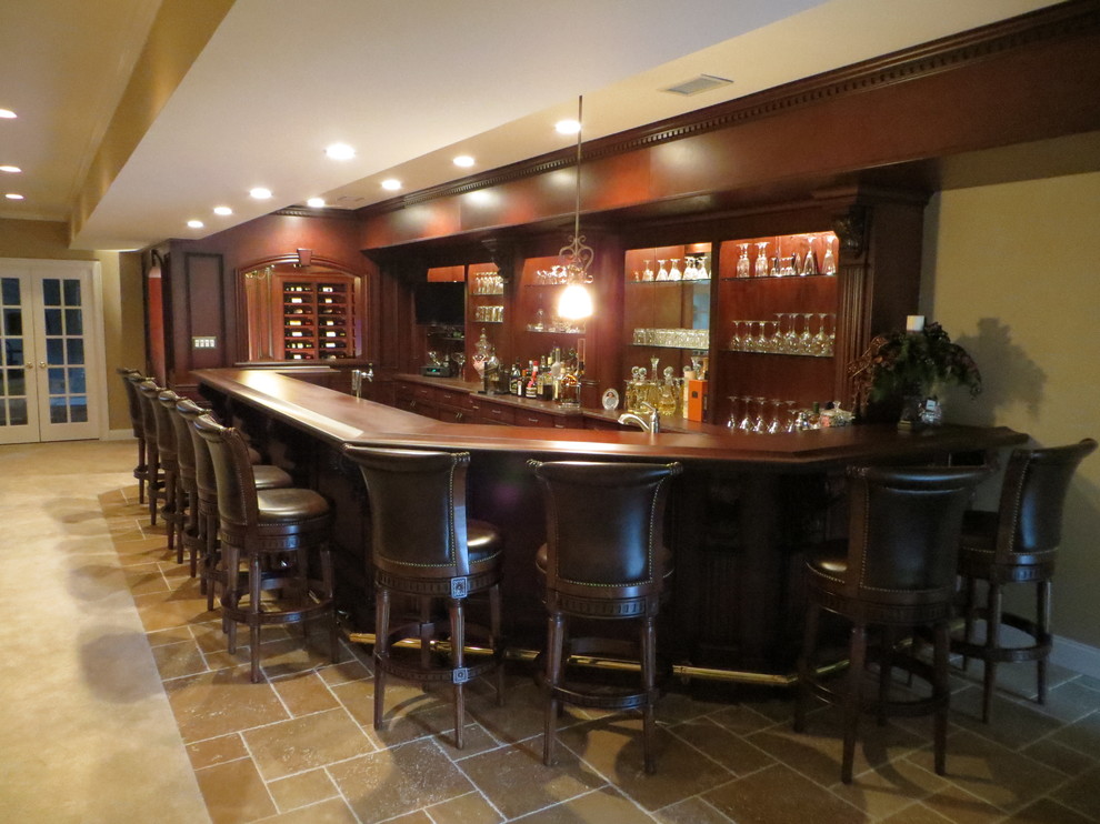 Inspiration for a large traditional u-shaped seated home bar in Philadelphia with medium wood cabinets, wood benchtops, travertine floors and brown floor.