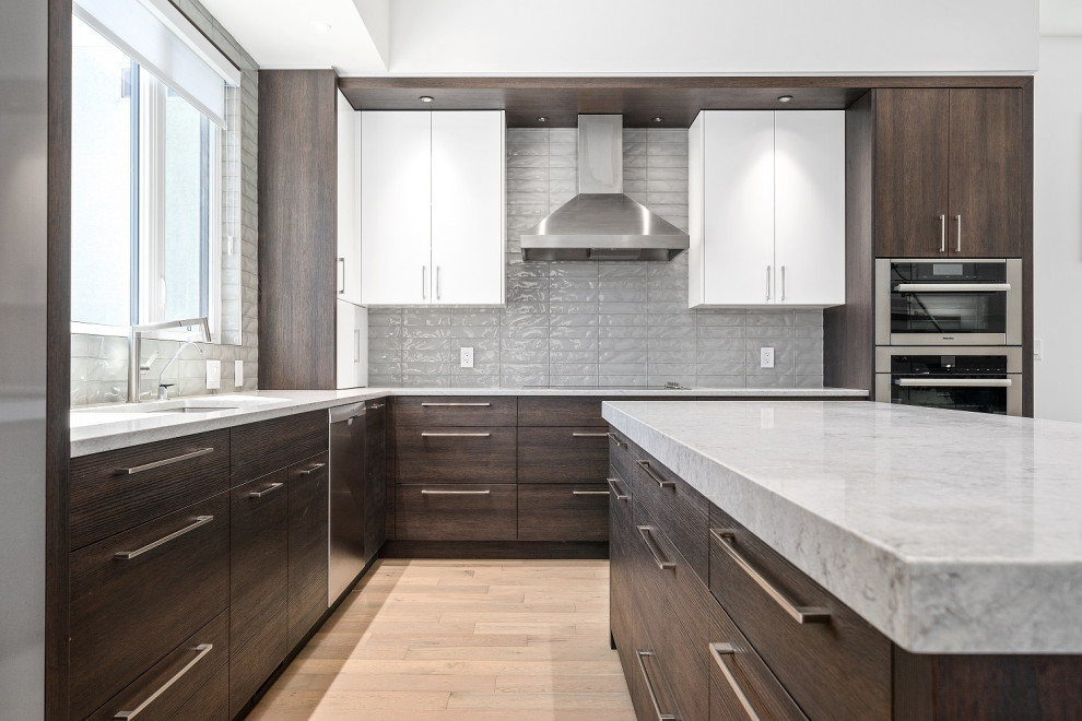 Inspiration for a mid-sized transitional l-shaped light wood floor and brown floor eat-in kitchen remodel in Calgary with an undermount sink, shaker cabinets, dark wood cabinets, quartzite countertops, gray backsplash, ceramic backsplash, stainless steel appliances, an island and beige countertops