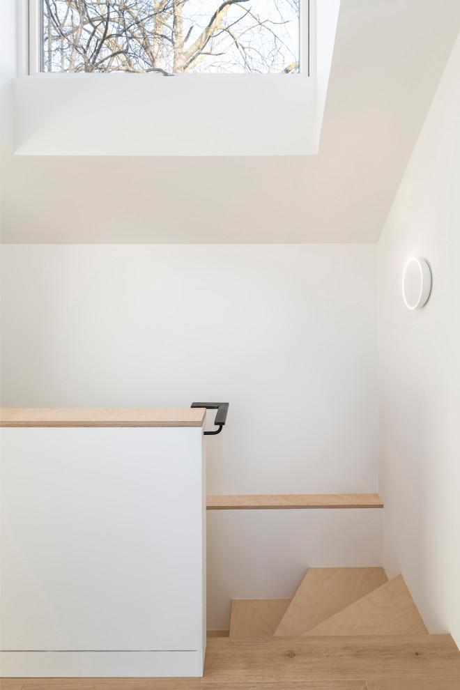 Cette photo montre un escalier tendance de taille moyenne avec des marches en bois, des contremarches en bois et un garde-corps en métal.