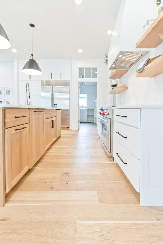 Inspiration for a large transitional light wood floor and brown floor kitchen pantry remodel in Other with an undermount sink, flat-panel cabinets, light wood cabinets, quartz countertops, an island and white countertops