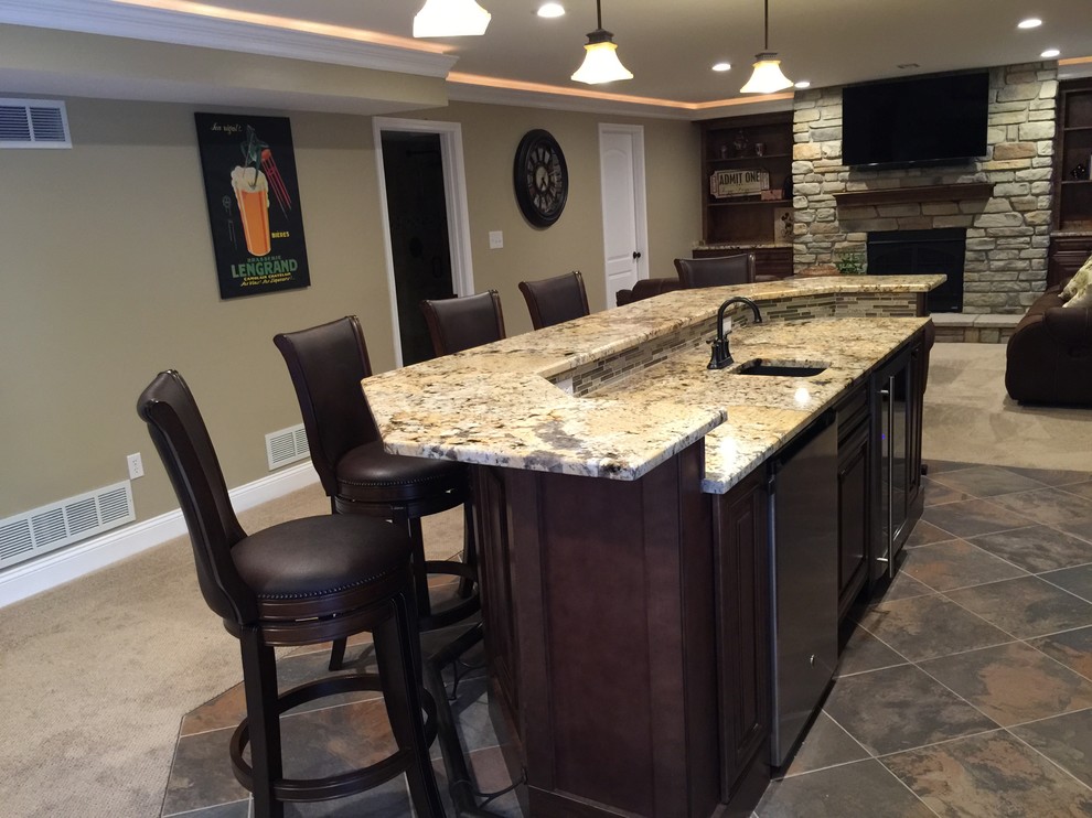 Inspiration for a large arts and crafts single-wall seated home bar in St Louis with an undermount sink, raised-panel cabinets, granite benchtops, beige splashback, stone tile splashback, ceramic floors and multi-coloured floor.
