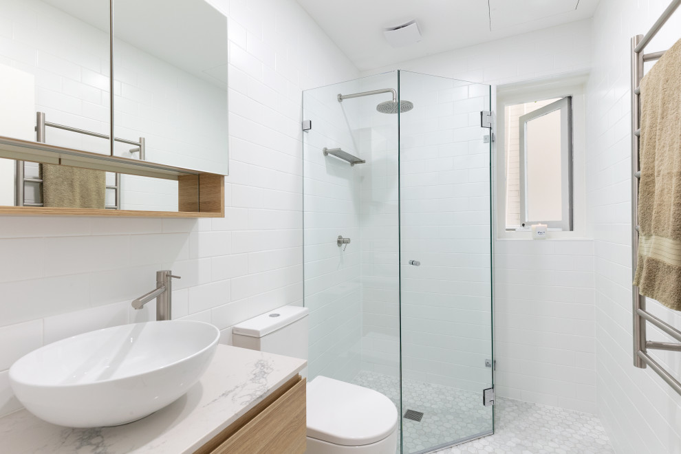 Small beach style 3/4 bathroom in Sydney with light wood cabinets, a corner shower, a wall-mount toilet, white tile, ceramic tile, white walls, mosaic tile floors, a vessel sink, engineered quartz benchtops, white floor and a hinged shower door.