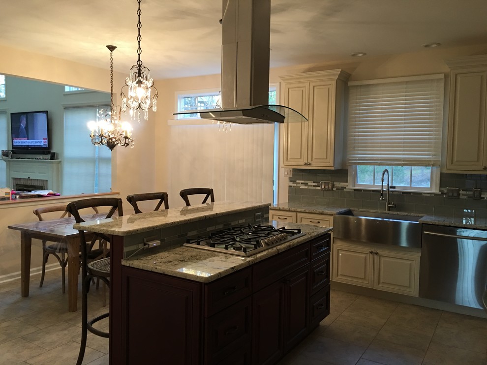 This is an example of a mid-sized traditional l-shaped eat-in kitchen in Philadelphia with a farmhouse sink, raised-panel cabinets, white cabinets, granite benchtops, green splashback, glass tile splashback, stainless steel appliances, linoleum floors and with island.