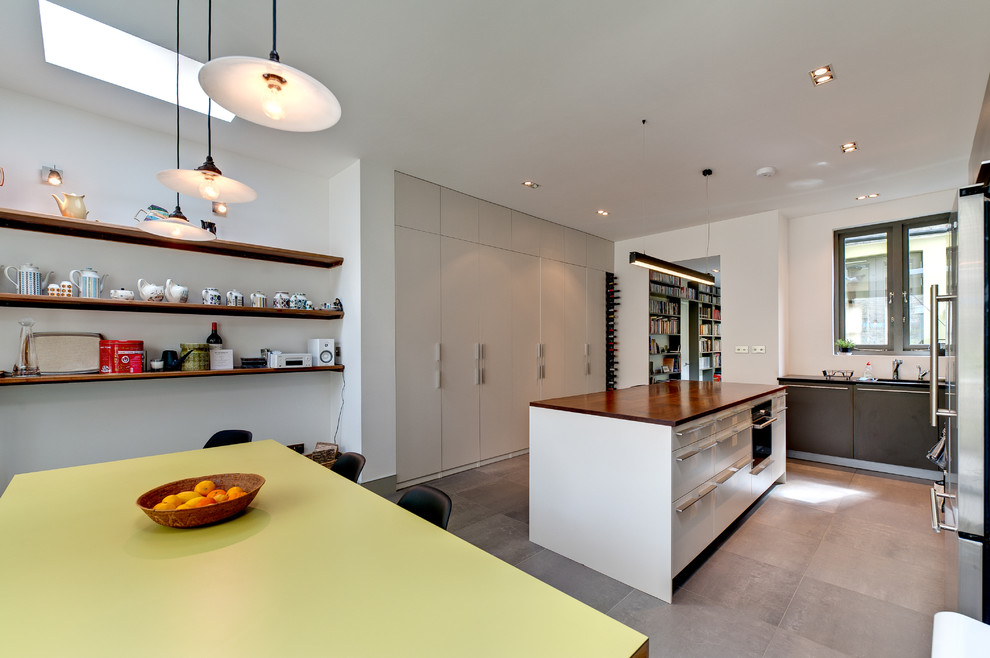 Inspiration for a contemporary eat-in kitchen in London with wood benchtops, white splashback and with island.