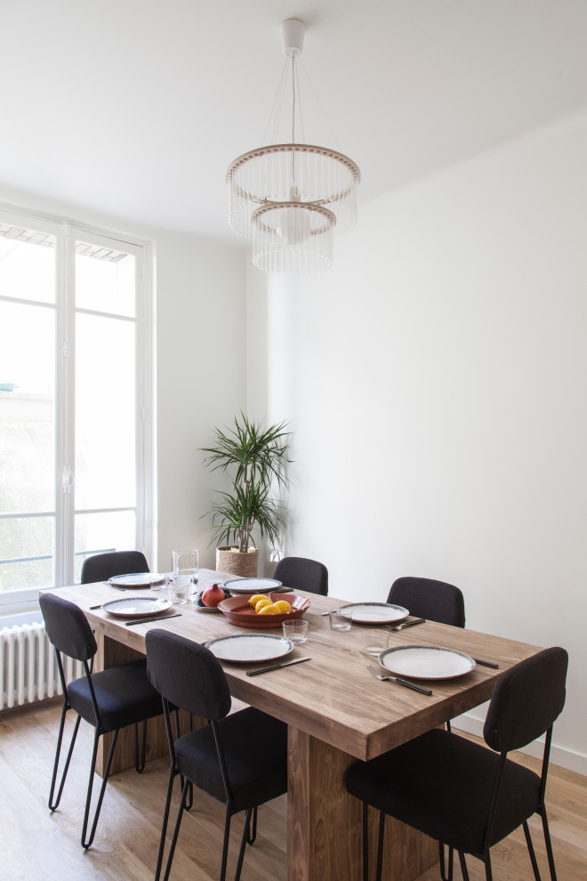 Mid-sized scandinavian open plan dining in Paris with white walls, light hardwood floors, no fireplace and beige floor.