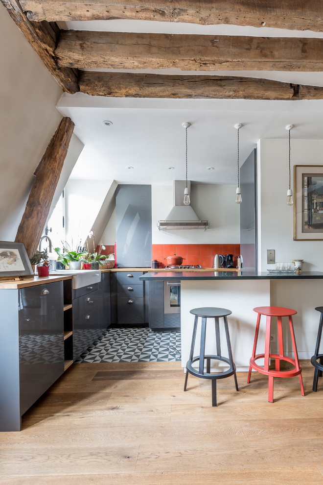Mediterranean l-shaped eat-in kitchen in Paris with a farmhouse sink, flat-panel cabinets, grey cabinets, red splashback, stainless steel appliances, light hardwood floors, a peninsula, beige floor and yellow benchtop.