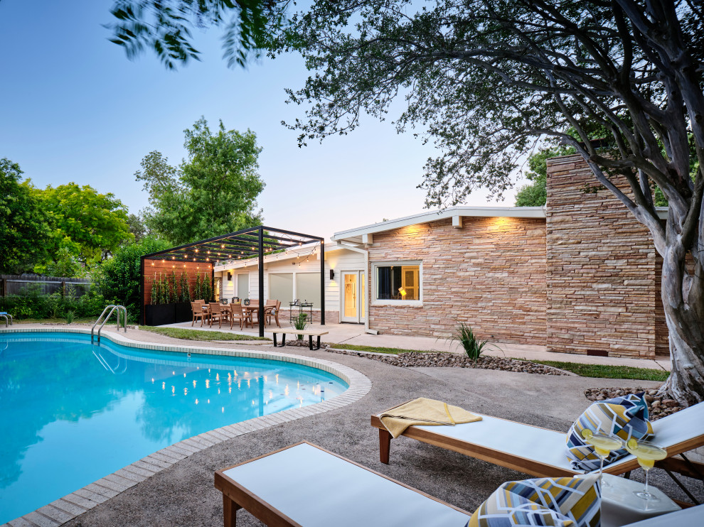 Diseño de piscina retro de tamaño medio tipo riñón en patio trasero con paisajismo de piscina y losas de hormigón