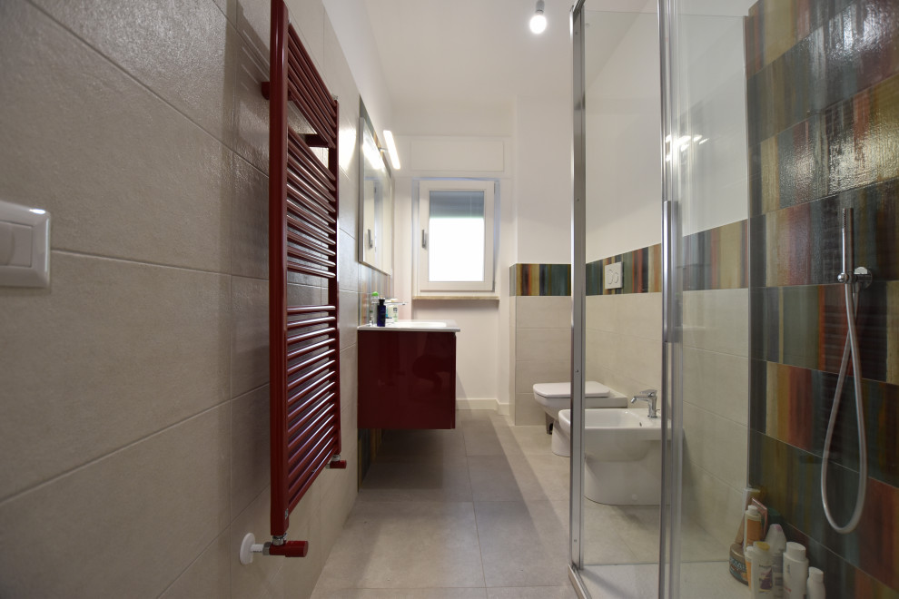 На фото: ванная комната среднего размера в стиле модернизм с плоскими фасадами, красными фасадами, угловым душем, раздельным унитазом, разноцветной плиткой, керамогранитной плиткой, белыми стенами, полом из керамогранита, душевой кабиной, подвесной раковиной, столешницей из искусственного камня, белым полом, душем с раздвижными дверями, белой столешницей, тумбой под одну раковину и подвесной тумбой с