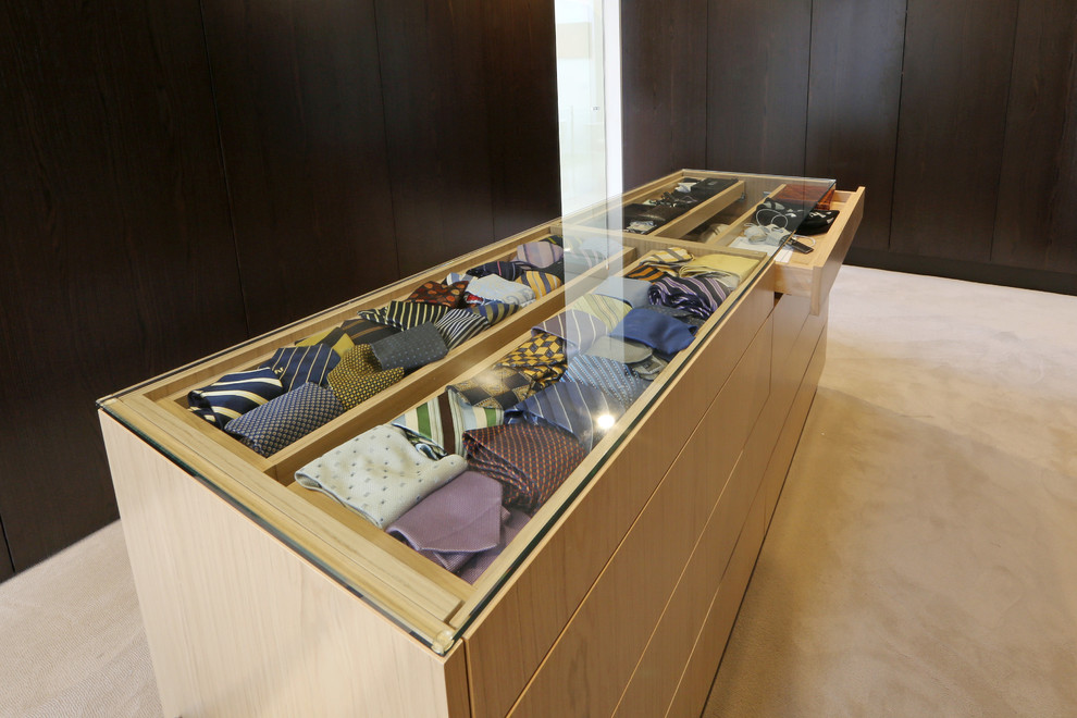 Photo of a large contemporary gender-neutral walk-in wardrobe in Melbourne with dark wood cabinets and carpet.