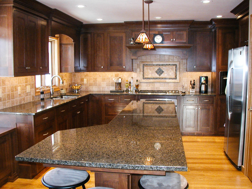 Mid-sized elegant l-shaped eat-in kitchen photo with an undermount sink, shaker cabinets, dark wood cabinets, granite countertops, stainless steel appliances and an island